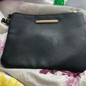 It’s a black leather, Steve Madden bag with gold and a wrist strap